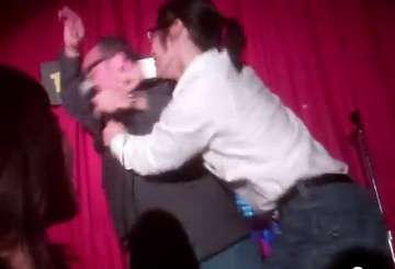 An audience member punching a standup comedian on stage.