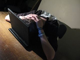 A guy at a desk grasping his head in frustration.